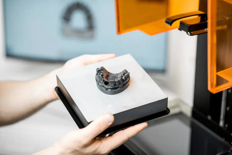 Dental technician removing jaw model from 3D printer